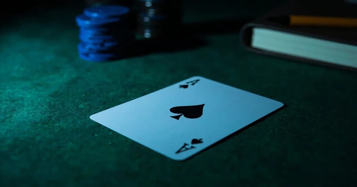 A single ace of spades on green felt beside blue chips and a closed notebook.