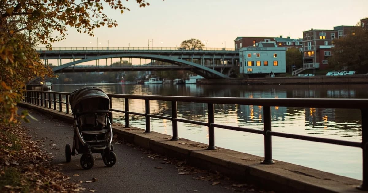 Schuylkill Banks trail with a stroller against a railing, Boathouse Row and bridge arches reflecting on the river.